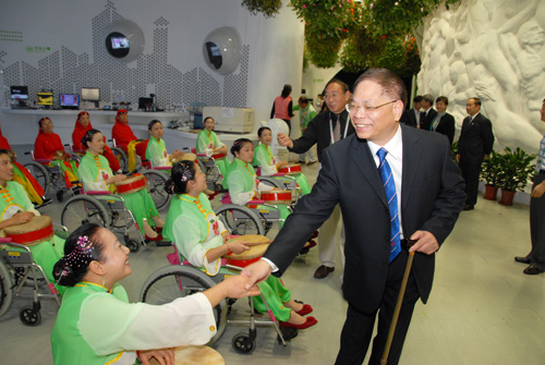 圖為中國殘聯(lián)黨組書記、理事長王新憲與寶山區(qū)輪椅鑼鼓隊隊員們親切握手